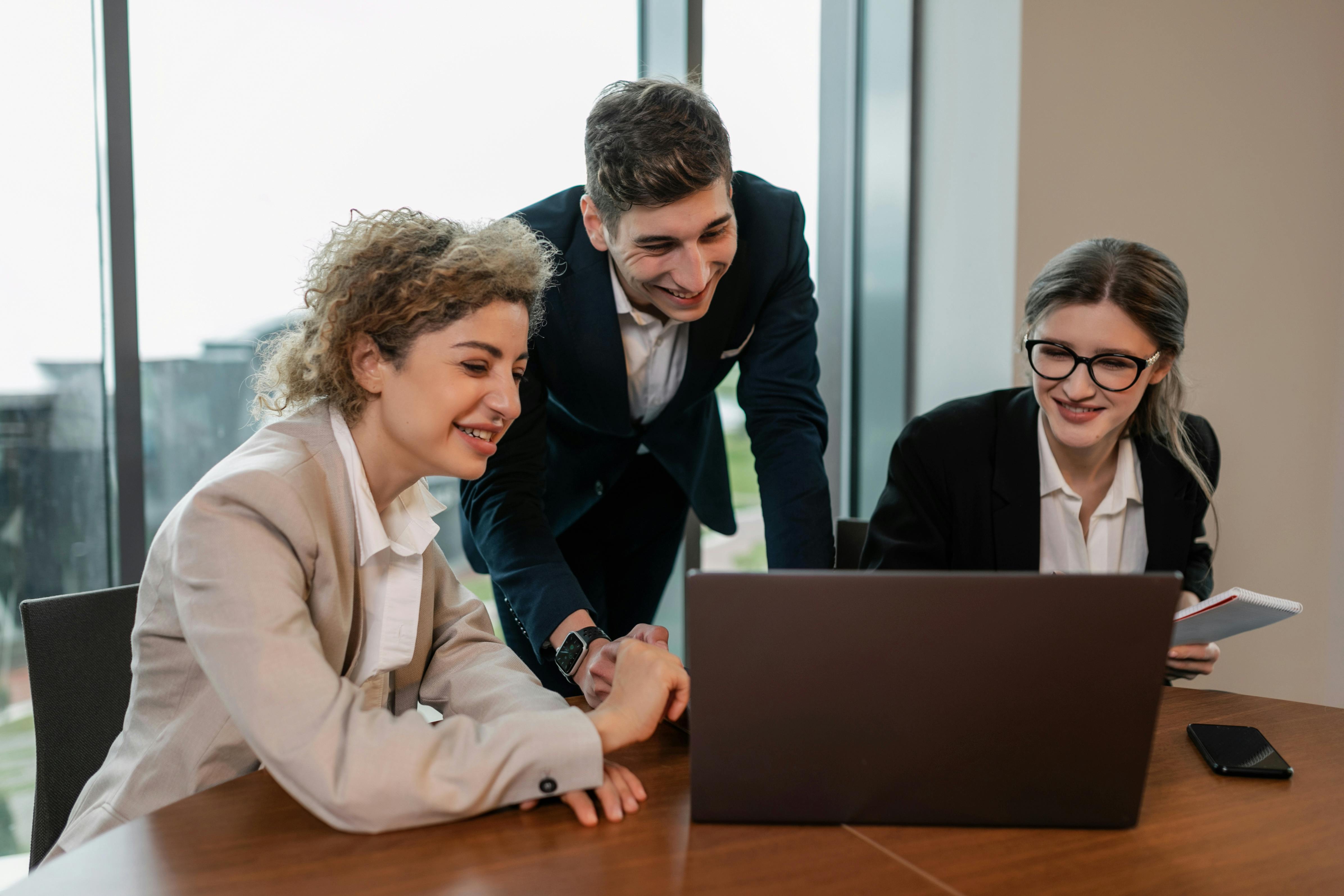 Professional team collaborating around a laptop in a modern office